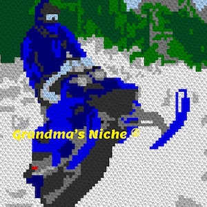May include: A blue snowmobile with a person in a blue suit riding it through a snowy landscape. The snowmobile has a black seat and a black and white design. The text "Grandma's Niche" is visible in the image.