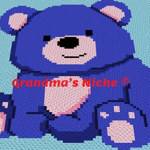 May include: A blue crocheted teddy bear with pink accents sits on a light blue background. The bear has a black nose and a smiling mouth. The text "Grandma's Niche" is visible in the center of the image.