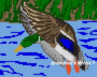 May include: A pixelated image of a brown and green duck with a blue wing, diving into blue water with white waves. The duck has a yellow beak and orange feet. The text "Grandma's Niche®" is in the bottom right corner of the image.