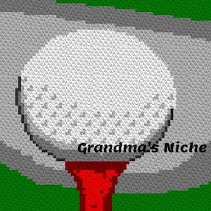 May include: A white golf ball sits on a red tee, ready to be hit. The ball is surrounded by a gray and green background, suggesting a golf course.