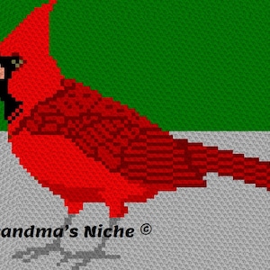 Puede incluir: Un pájaro cardenal rojo con cabeza y pico negros, de pie sobre un fondo gris. El pájaro está mirando hacia el lado izquierdo de la imagen. El texto "Grandma's Niche®" está en la parte inferior de la imagen.