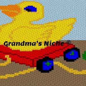 May include: A yellow rubber ducky riding in a red toy wagon with blue wheels. The wagon has a yellow rope attached to it. The background is a light blue and brown crochet pattern. The text "Grandma's Niche®" is visible on the wagon.