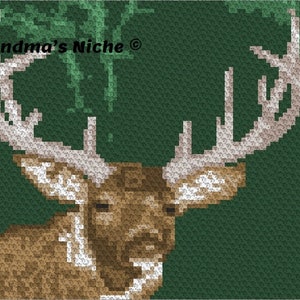 May include: A brown deer with large antlers stands in a green forest. The deer's head is turned to the side, and its eyes are closed. The antlers are white and have many points. The deer is surrounded by green leaves and branches.