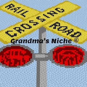 Puede incluir: Colgante de pared tejido a crochet con un cartel de cruce de ferrocarril amarillo y negro con el texto "Rail Crossing Road" y dos luces rojas intermitentes. El cartel está sobre un fondo azul con el texto "Grandma's Niche" debajo.