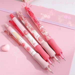 May include: Four pink pens with floral designs and the words "Rose Love" and "Love" printed on them. The pens have a soft, pink foam grip.