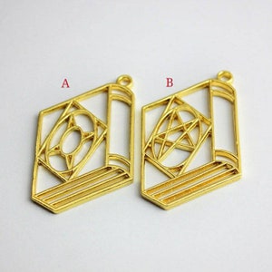 May include: Two gold-colored metal book charms with different designs. The charm on the left has a star inside a circle. The charm on the right has a pentagram inside a circle.