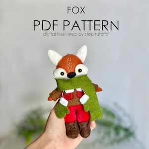 Könnte beinhalten: Ein PDF-Muster zum Nähen eines Fuchs-Plüschtiers. Der Fuchs trägt einen grünen Schal, eine rote Hose und braune Stiefel. Das Muster enthält Schritt-für-Schritt-Anleitungen.