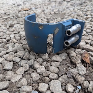 May include: A blue plastic helmet with three silver exhaust ports on the side. The helmet has a worn, weathered look.