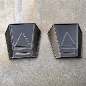 May include: Two black metal wall sconces with a triangular design and a rectangular base.