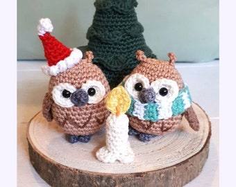 May include: Two crocheted owls, one wearing a Santa hat and the other a green and white scarf, stand in front of a crocheted Christmas tree with a crocheted candle between them. The owls and tree are on a wooden slice. The text "Christmas Owls - crochet pattern -" is above the image and "WWW.BIRDSANDCRICKETS.COM" is below the image.