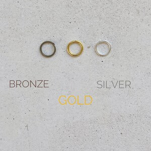 Puede incluir: Tres anillos de salto en bronce, oro y plata.