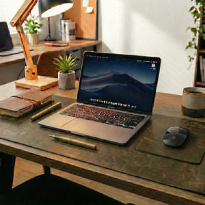 Warm studio angle, olive green crazy horse finish full grain leather desk mat under laptop, mouse, wooden desk
