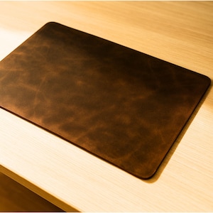 Close-up edge view, distressed brown crazy horse full grain leather desk mat, visible grain and patina
