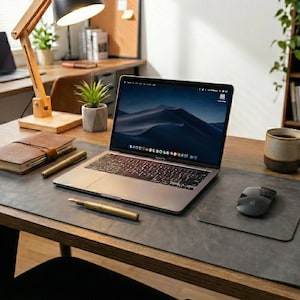 Cool gray full grain leather desk mat, slim profile on wood desk, laptop, notebook, soft natural light