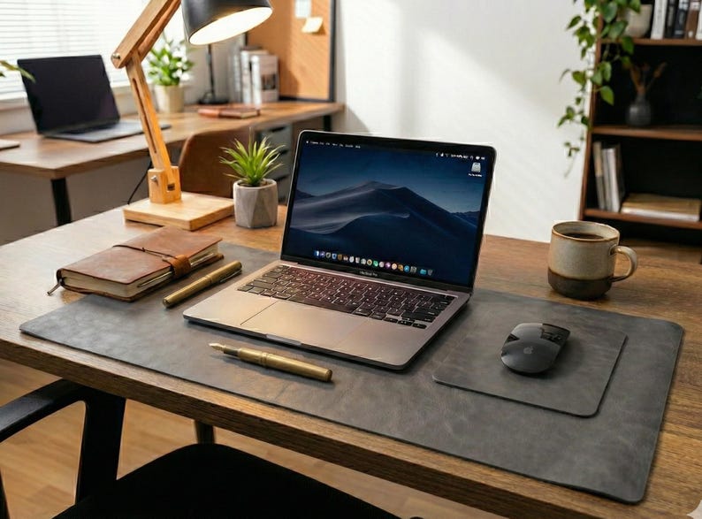 Cool gray full grain leather desk mat, slim profile on wood desk, laptop, notebook, soft natural light