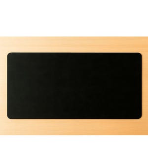 Flat black full grain leather desk mat, clean rectangular leather desk pad on light wood surface
