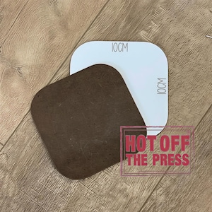 a brown square object placed on a wooden surface, with a white rectangular object above it. There is a red text overlay that says "HOT OFF THE PRESS".