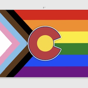 May include: A 3-inch by 2.2-inch flag with a rainbow pride flag design and a red circle with a yellow circle in the center, representing the Colorado state flag.
