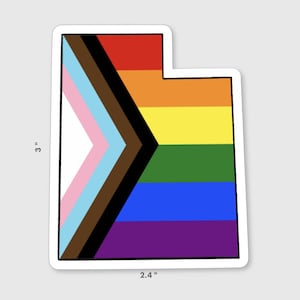 May include: A sticker of the state of Utah with a pride flag design. The flag features a black and brown chevron with a pink, light blue, and white chevron on top. The bottom of the sticker features the colors of the rainbow pride flag: red, orange, yellow, green, blue, and purple.