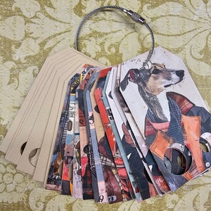 May include: A collection of paper tags attached to a silver wire loop. The tags feature various designs, including a dog wearing a coat, abstract patterns, and numbers. Some tags are blank, while others have cut-out circles.