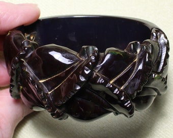 May include: A dark brown carved plastic bangle bracelet with a textured, leaf-like design.