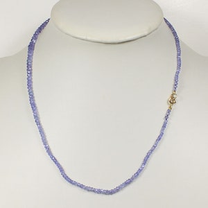 May include: A delicate necklace made of small, light purple beads. The necklace is approximately 18 inches long and has a gold clasp.