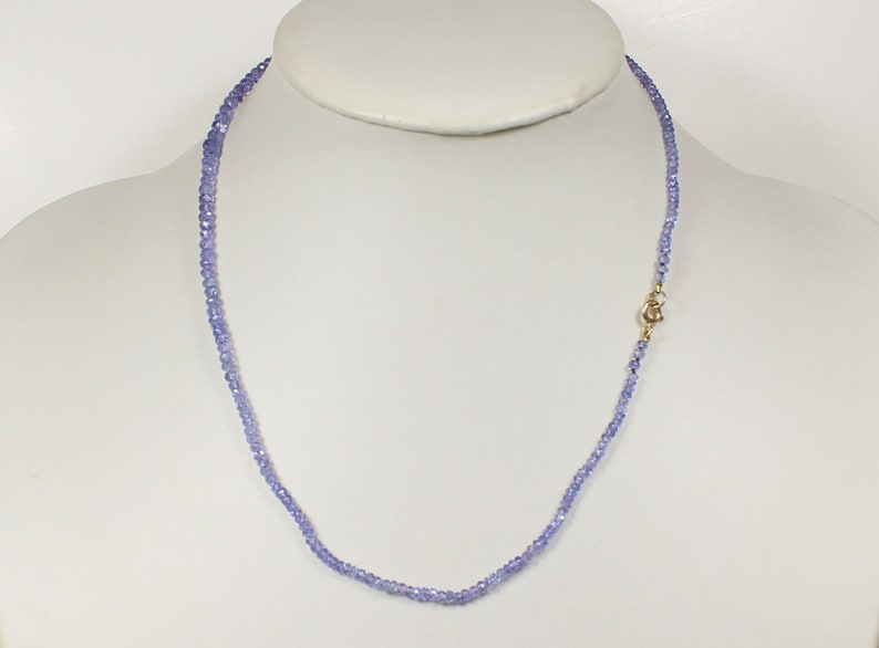 May include: A delicate necklace made of small, light purple beads. The necklace is approximately 18 inches long and has a gold clasp.