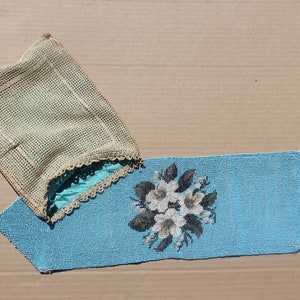 Puede incluir: Un camino de mesa azul de cuentas con un diseño floral y una bolsa de ganchillo beige.