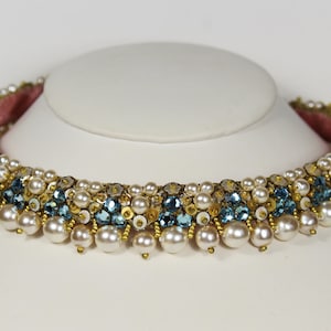 May include: A gold and white beaded choker necklace with blue gemstones. The necklace has a row of pearls along the bottom.