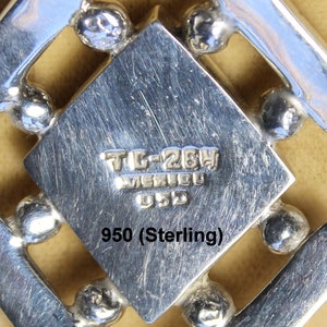 May include: Close-up of a silver pendant with a geometric design. The pendant is marked "TL-264 MEXICO 950" and "950 (Sterling)".