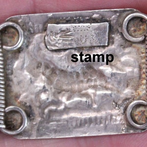 May include: Silver bracelet with a textured design and a stamp that reads "stamp".