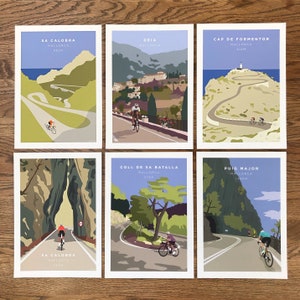 Six Mallorca cycling themed prints by JensCyclingArt shown laid out together on a table from above. They include Sa Calobra, Deia, Cap de Formentor, Sa Calobra Tunnel, Coll de Sa Batalla and Puig Major.