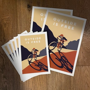 May include: A set of four prints with a mountain biking theme. The prints feature a cyclist riding a mountain bike with the text "Outside is Free" in a bold, white font. The prints are in a vintage style with a brown and orange color scheme.