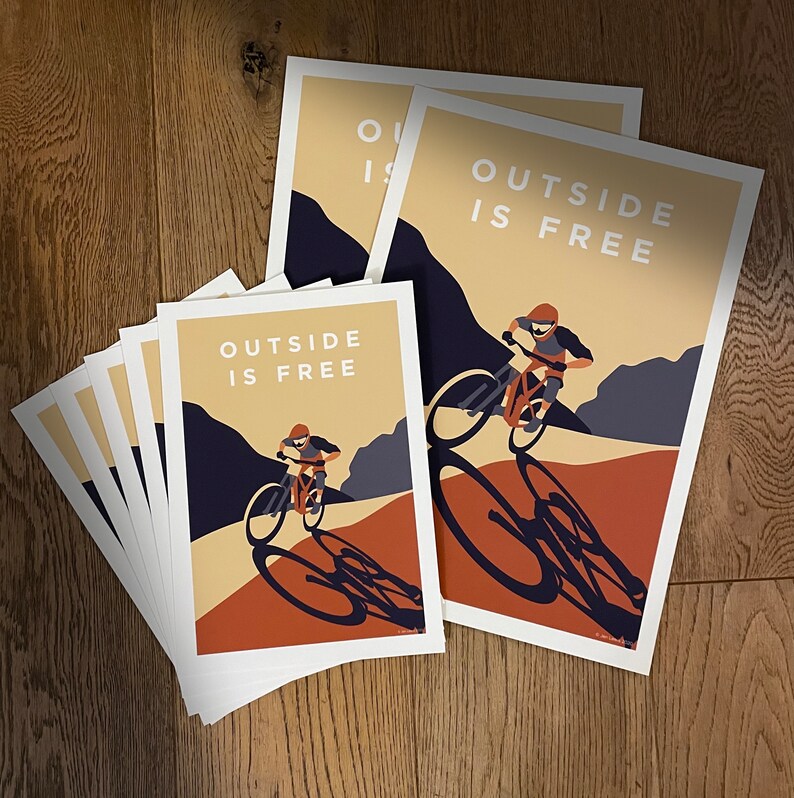 May include: A set of four prints with a mountain biking theme. The prints feature a cyclist riding a mountain bike with the text "Outside is Free" in a bold, white font. The prints are in a vintage style with a brown and orange color scheme.