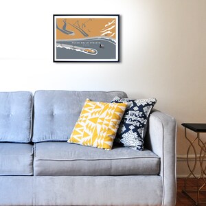 Room setting with grey sofa and wall art Passo Dello Stelvio  - Almost at the Summit Cycling Print. Simplistic style mainly grey and mustard colour design, looking down on cyclist ascending the hairpin bends on Stelvio Pass in Italy.