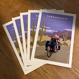 TandemWoW Guinness World Record Holders Cycling Prints showing the women tandem cyclists riding through a desert with cacti and mountains on their world record breaking challenge.
