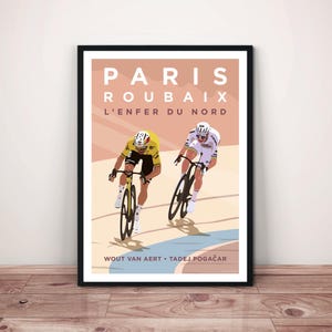 May include: Framed art print featuring a cycling race scene. The poster has the words "Paris Roubaix L'Enfer Du Nord" at the top. Two cyclists are depicted in action, with the names Wout Van Aert and Tadej Pogačar at the bottom. The artwork is in a minimalist style.