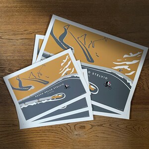 Passo Dello Stelvio  - Almost at the Summit Cycling Prints shown in 2 sizes but available in 3. Simplistic style mainly grey and mustard colour design, looking down on cyclist ascending the hairpin bends on Stelvio Pass in Italy.