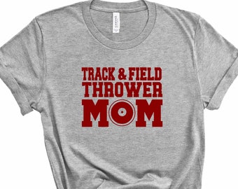 May include: Gray t-shirt with the text "Track & Field Thrower Mom" in red with a red weight plate icon.