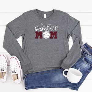 May include: A gray long-sleeved shirt with the text "basketball mom" in white lettering and a maroon basketball graphic.