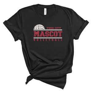 May include: Black t-shirt with a red and white volleyball graphic. The text "YOUR CITY MASCOT VOLLEYBALL" is printed on the shirt.