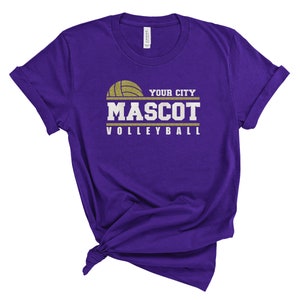 May include: Purple t-shirt with a gold volleyball graphic and the text "YOUR CITY MASCOT VOLLEYBALL"
