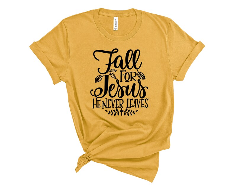 May include: A mustard yellow t-shirt with the text "Fall for Jesus He Never Leaves" in black lettering. The text is surrounded by small leaf designs.