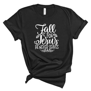 May include: Black t-shirt with white text that reads "Fall for Jesus He Never Leaves" with a leaf design.