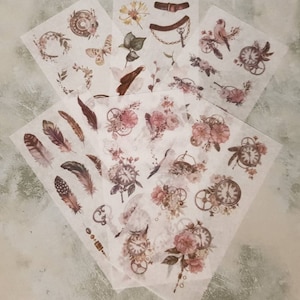 Könnte beinhalten: Ein Set aus sechs Blättern aus klarem, durchsichtigem Papier mit verschiedenen Designs im Vintage-Stil. Die Designs umfassen Federn, Blumen, Zahnräder, Uhren, Schmetterlinge, Vögel und Schlüssel. Die Blätter sind perfekt für Scrapbooking, Kartenherstellung und andere Bastelprojekte.