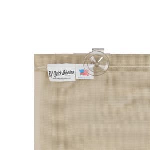 May include: Close-up of a beige RV Quick Shades window covering. The shade has a grid-like pattern and a clear suction cup. A white label displays the brand name, website, and a small American flag, indicating it's made in the USA.