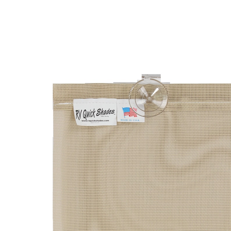 May include: Close-up of a beige RV Quick Shades window covering. The shade has a grid-like pattern and a clear suction cup. A white label displays the brand name, website, and a small American flag, indicating it's made in the USA.
