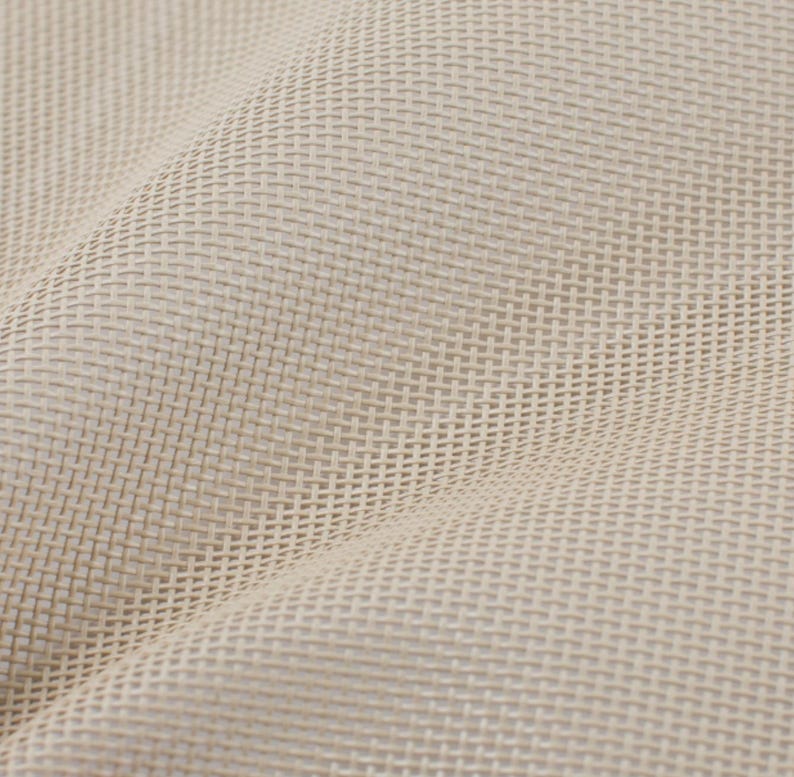 May include: Close-up of a beige woven fabric with a textured, basket-weave pattern. The fabric is folded, creating shadows and highlighting the weave's intricate detail. The neutral color suggests versatility for various applications.
