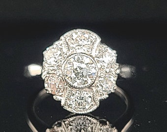 May include: A silver ring with a large, round, clear diamond surrounded by smaller diamonds in a floral design.