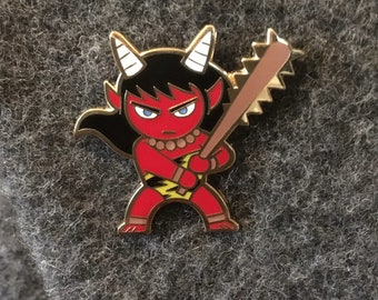May include: A red and black enamel pin of a cartoon demon holding a wooden baseball bat with a serrated edge. The demon has horns, white eyes, and a yellow lightning bolt on its chest.